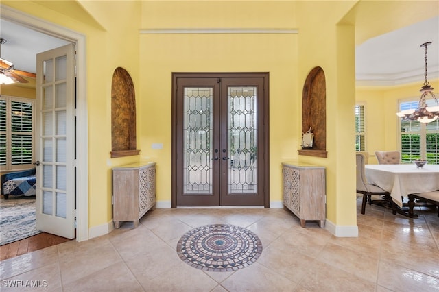 entrance foyer featuring tile patterned flooring, french doors, baseboards, and ceiling fan with notable chandelier