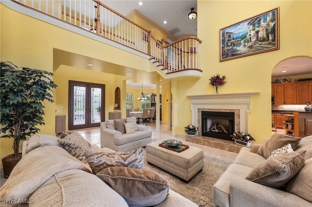 living area featuring arched walkways, french doors, a tiled fireplace, a high ceiling, and ornamental molding