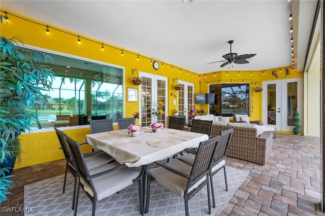 view of patio with glass enclosure, an outdoor hangout area, a ceiling fan, french doors, and outdoor dining space