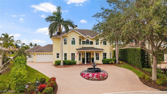 view of front of home featuring a tiled roof, decorative driveway, a chimney, and an attached garage