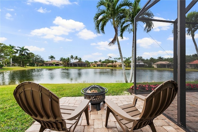 exterior space with a water view, glass enclosure, and a fire pit