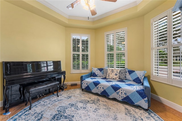 bedroom featuring baseboards, a raised ceiling, wood finished floors, and crown molding