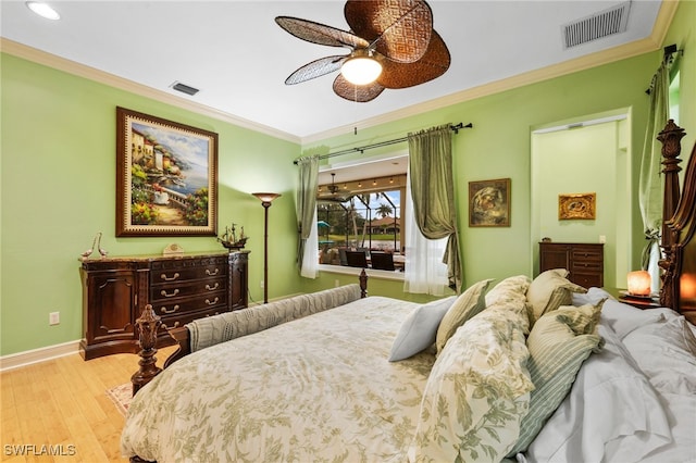 bedroom with visible vents, crown molding, baseboards, and wood finished floors