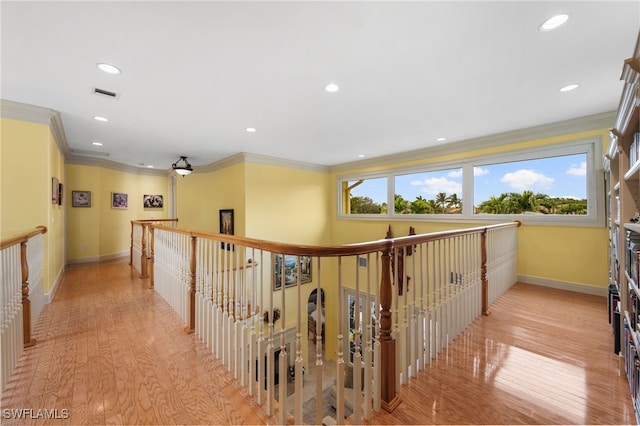 hall featuring light wood finished floors, ornamental molding, visible vents, and baseboards