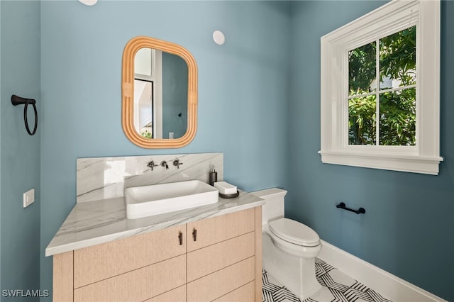 half bath featuring toilet, baseboards, vanity, and tile patterned flooring