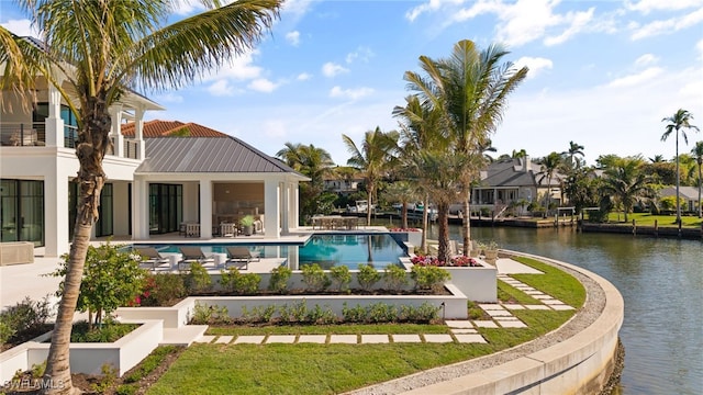 swimming pool with a water view, a patio, and a yard