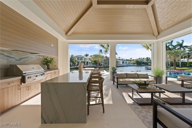 view of patio with outdoor lounge area, a water view, a bar, grilling area, and an outdoor kitchen