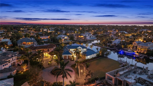 aerial view at dusk featuring a water view