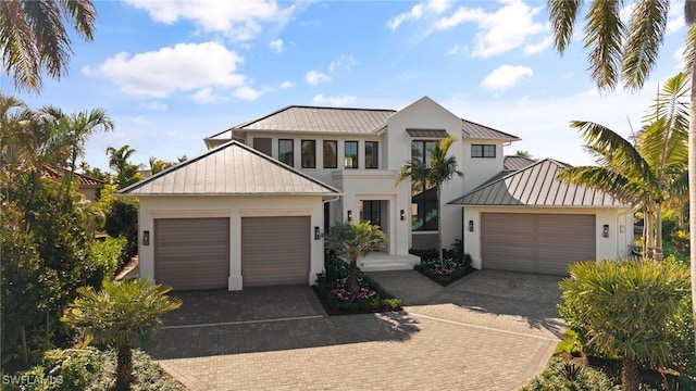 view of front of property with a standing seam roof, metal roof, stucco siding, decorative driveway, and an attached garage