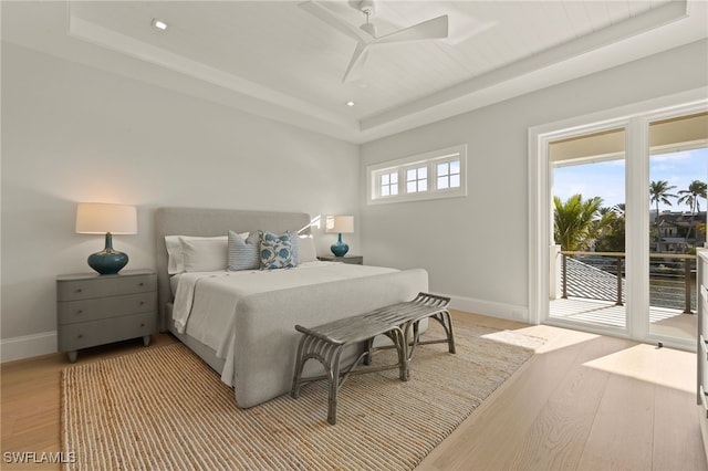bedroom featuring a tray ceiling, access to exterior, baseboards, light wood-style floors, and recessed lighting