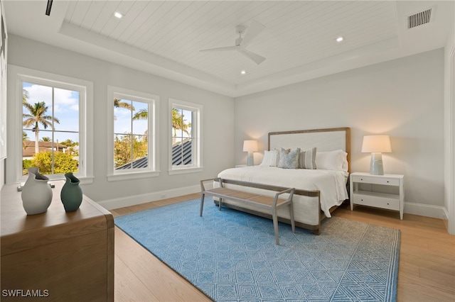 bedroom with a tray ceiling, wood finished floors, baseboards, wooden ceiling, and recessed lighting