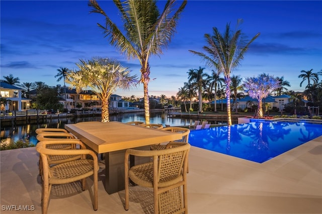 pool at dusk with a patio and a water view