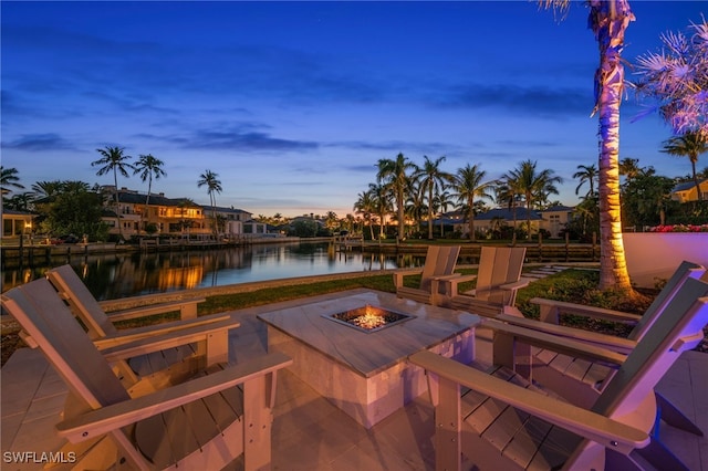 patio terrace at dusk featuring a water view and an outdoor fire pit