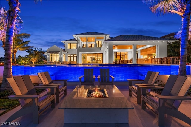 pool at twilight featuring an outdoor fire pit, an outdoor pool, and a patio area