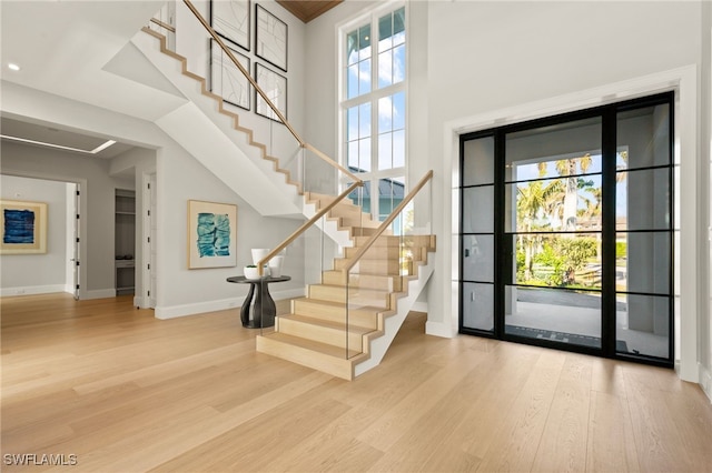 entrance foyer with stairs, wood finished floors, baseboards, and a high ceiling