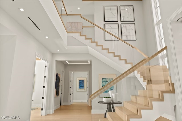 staircase featuring a towering ceiling and hardwood / wood-style flooring