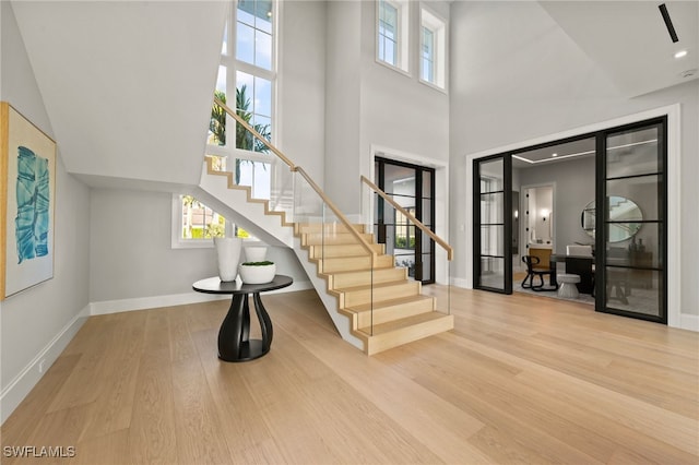 staircase with a towering ceiling and hardwood / wood-style floors