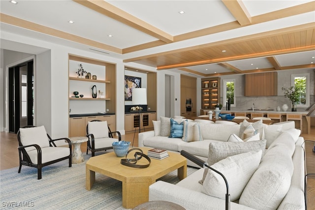 living room featuring beam ceiling, sink, built in shelves, and light hardwood / wood-style flooring