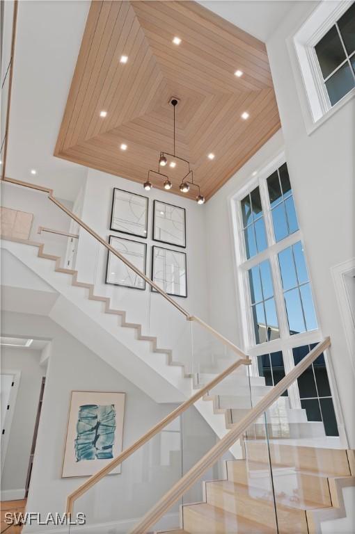stairway featuring a towering ceiling, wood ceiling, recessed lighting, and a chandelier