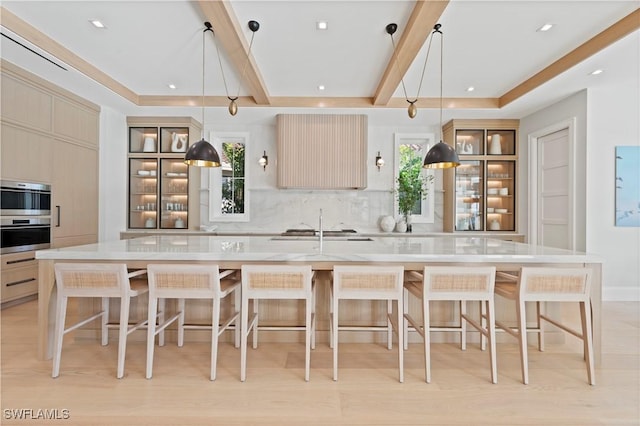 kitchen featuring tasteful backsplash, light countertops, stainless steel appliances, a large island, and light wood-style flooring