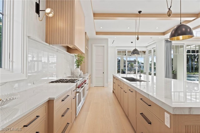 kitchen featuring a sink, double oven range, light wood-style flooring, tasteful backsplash, and light brown cabinetry
