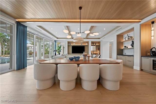 dining room featuring light wood-type flooring, built in features, a chandelier, bar, and coffered ceiling