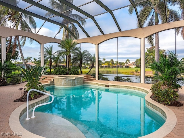 view of pool with an in ground hot tub, a water view, glass enclosure, and a patio area