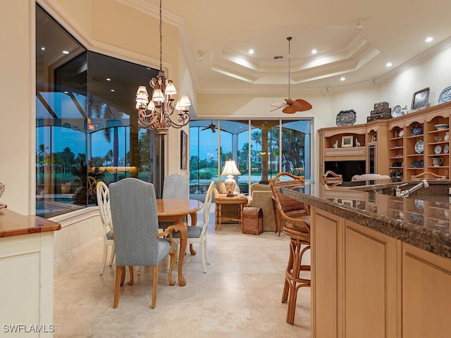 dining area featuring a raised ceiling, ornamental molding, and ceiling fan