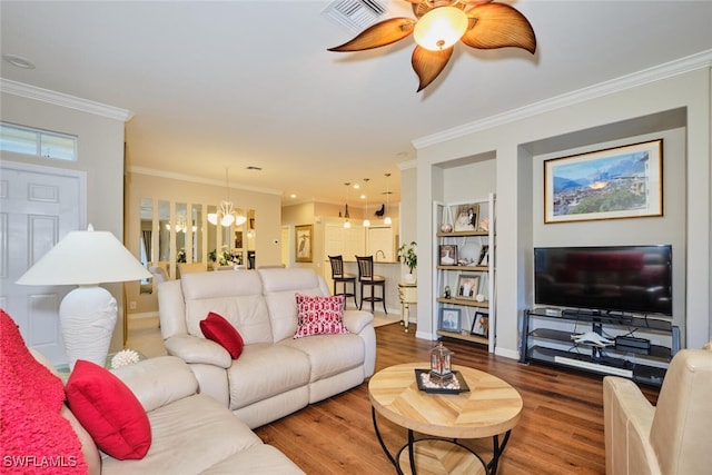 living room with built in shelves, a chandelier, hardwood / wood-style flooring, and ornamental molding