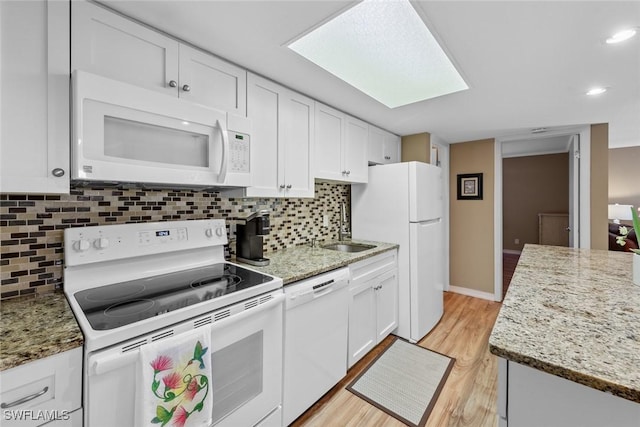 kitchen with light hardwood / wood-style floors, white cabinets, light stone counters, and white appliances