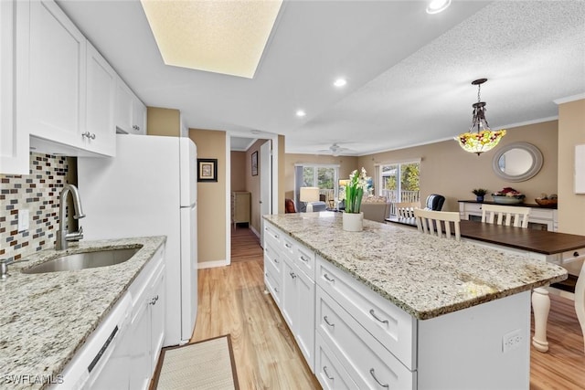 kitchen featuring ceiling fan, sink, white cabinets, and a kitchen island