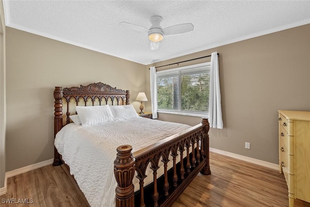 bedroom featuring a textured ceiling, ceiling fan, ornamental molding, and hardwood / wood-style flooring