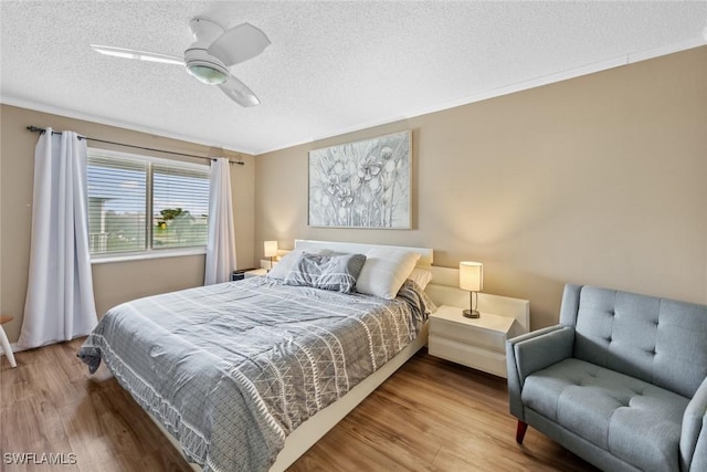 bedroom with a textured ceiling, ceiling fan, ornamental molding, and hardwood / wood-style flooring