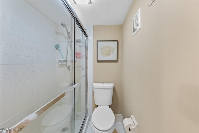 bathroom featuring toilet and a shower with shower door