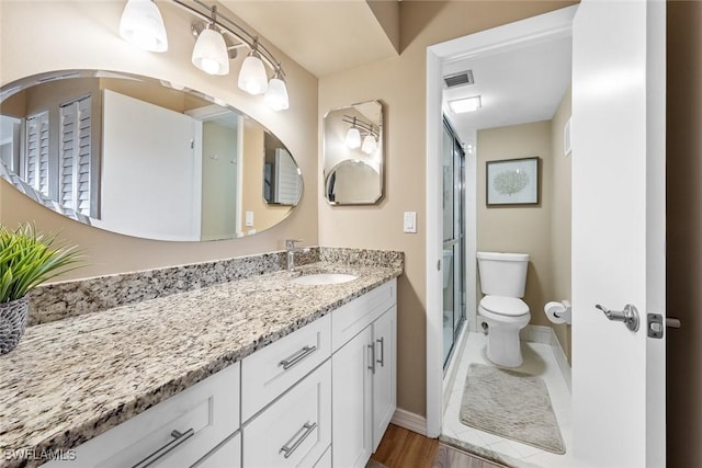 bathroom featuring toilet, a shower with shower door, hardwood / wood-style flooring, and vanity