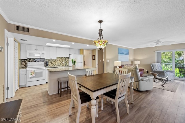 dining room featuring a textured ceiling, ceiling fan, ornamental molding, and light hardwood / wood-style flooring