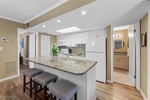 kitchen with white cabinetry, white appliances, light hardwood / wood-style flooring, and a kitchen island