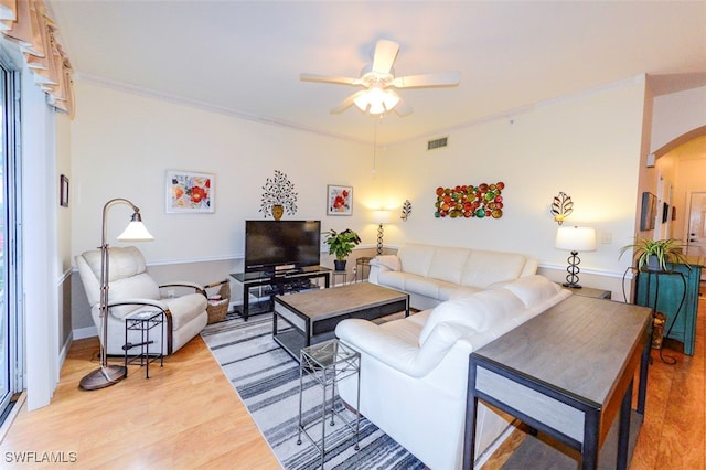 living room with crown molding, light hardwood / wood-style floors, and ceiling fan