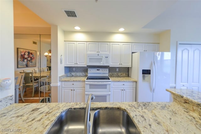 kitchen with white cabinetry, light stone counters, white appliances, and decorative light fixtures