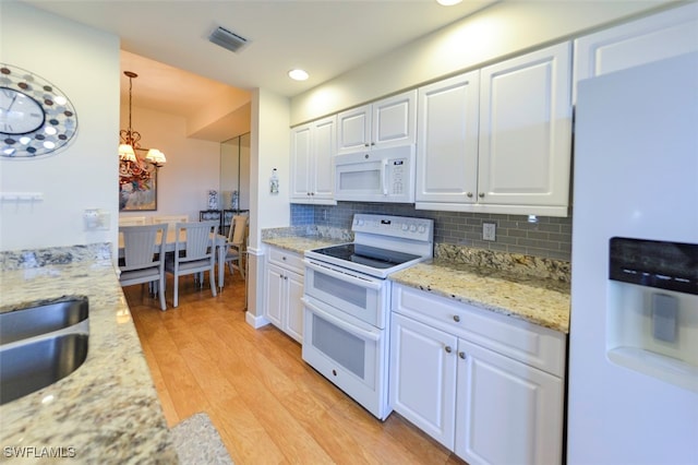 kitchen featuring hanging light fixtures, white cabinets, white appliances, and light hardwood / wood-style flooring