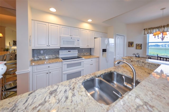 kitchen featuring white cabinetry, sink, white appliances, and hanging light fixtures