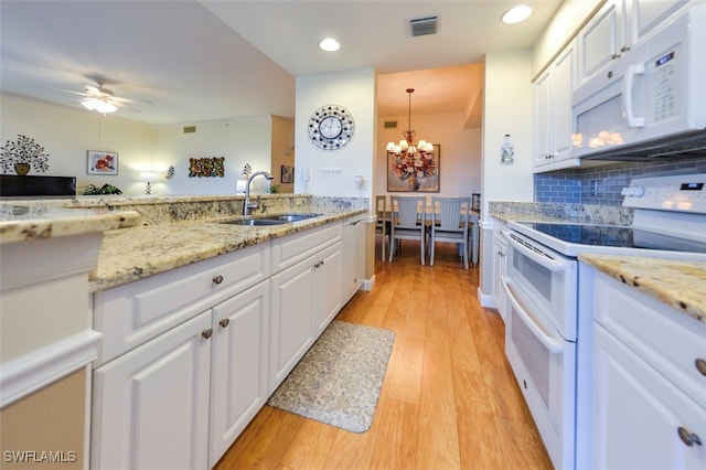 kitchen featuring white cabinetry, hanging light fixtures, white appliances, and sink