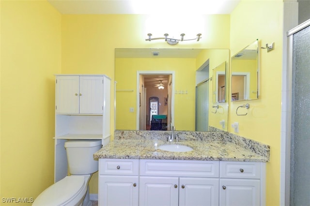 bathroom with vanity, a shower with door, and toilet