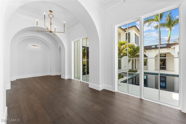 spare room with crown molding, dark wood-type flooring, and an inviting chandelier