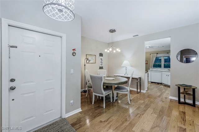 dining area with ceiling fan with notable chandelier and light hardwood / wood-style floors