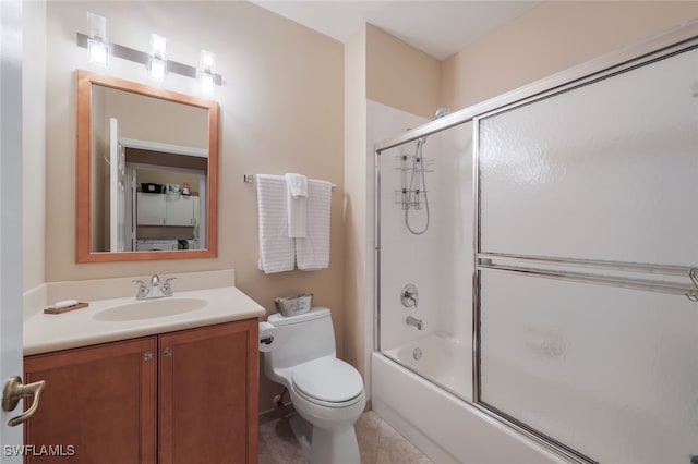 full bathroom with bath / shower combo with glass door, toilet, vanity, and tile patterned flooring