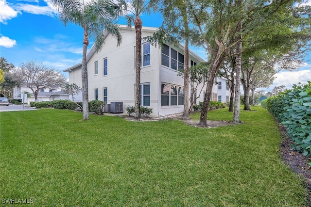 view of side of home with central AC unit and a lawn