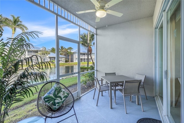 sunroom / solarium featuring ceiling fan and a water view