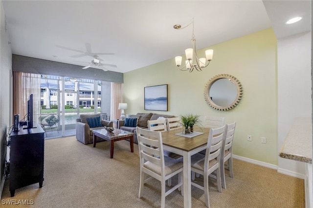 dining room featuring light colored carpet and ceiling fan with notable chandelier