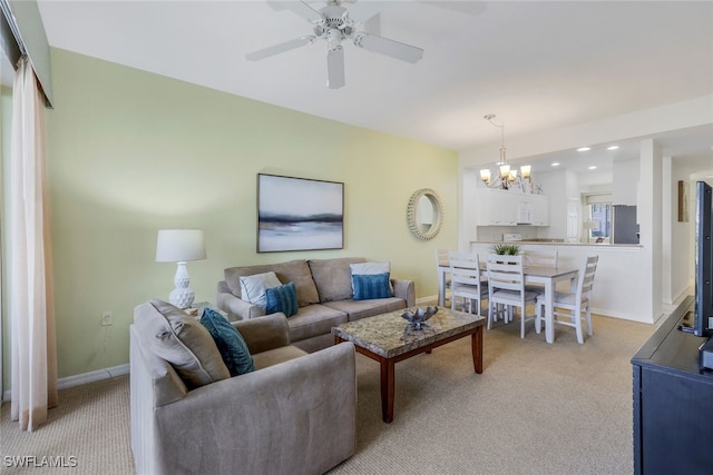 living room featuring ceiling fan with notable chandelier and light colored carpet